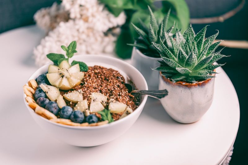 High fiber meal of buckwheat and fruit in bowl next to succulent plant