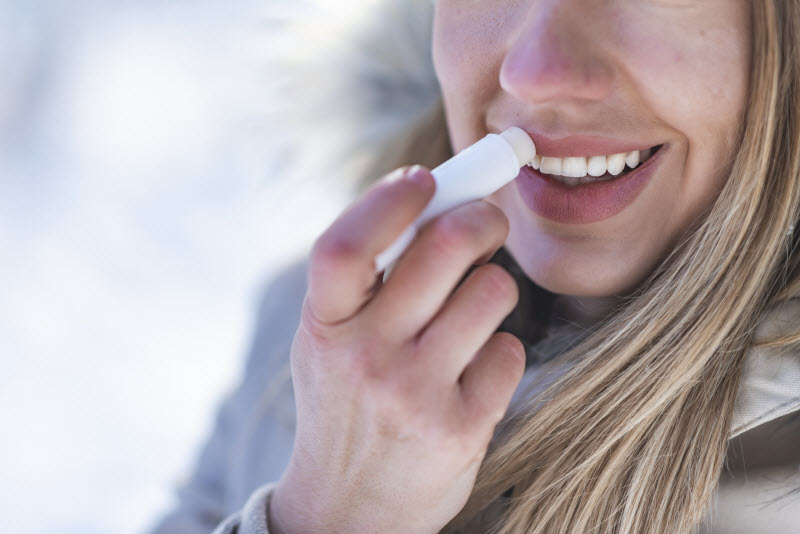 Blonde Woman in Winter Coat Using Best Natural Lip Moisturizer to Protect Her Lips From Cold Weather | Vitacost.com/blog