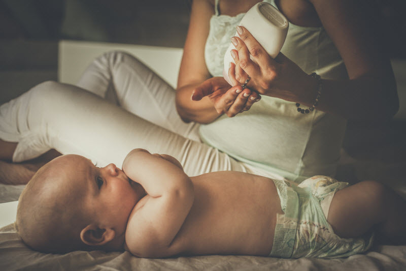 Torso View of Mother Applying Lotion to Infant to Represent How to Care Baby Skin Winter | Vitacost.com/blog