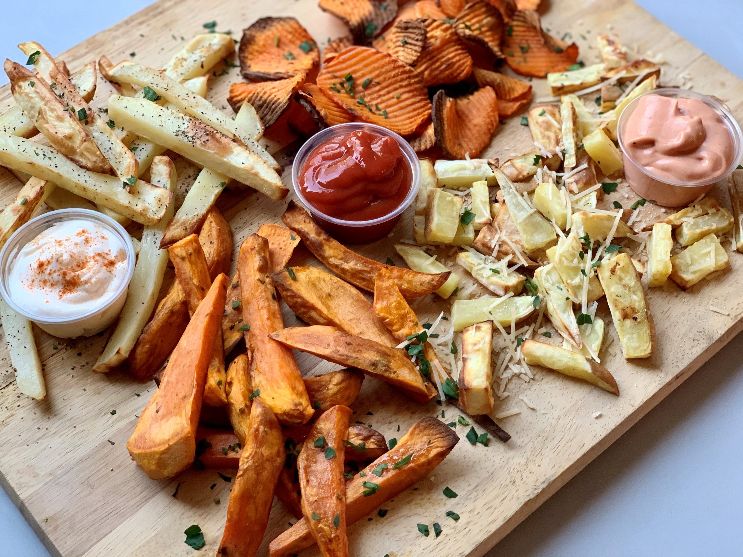 Homemade air fryer French fries displayed on cutting board with dipping sauces