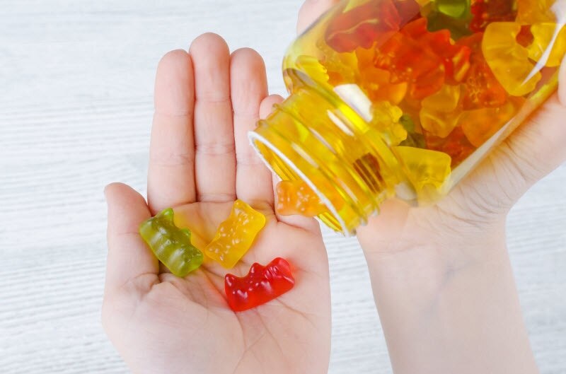 Child's Hands Holding Bottle of Colorful Gummy Vitamins to Represent Concept of How Much Vitamin D for Kids is Appropriate | Vitacost.com/blog