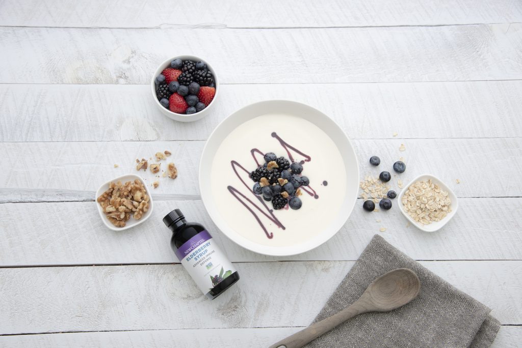 Top View of Bowl of Yogurt with Elderberry Drizzle Next to Smaller Bowls of Fruits, Nuts and Oats | Vitacost Blog