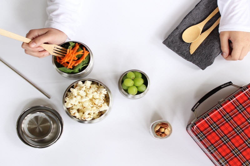 Overhead View of Round Reusable Metal Containers Replacing Single-Use Plastics Filled With Assorted Snacks on White Table | Vitacost.com/blog