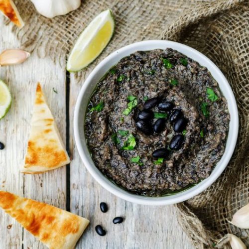 Top View of Black Bean Hummus in White Bowl on White Wood | Vitacost Blog