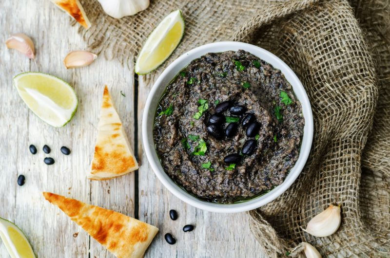 Top View of Black Bean Hummus in White Bowl on White Wood | Vitacost Blog