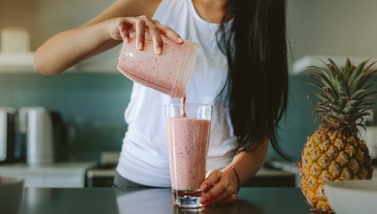 Torso View of Woman Leaning How to Get More Protein Pouring Smoothie From Blender Into Glass | Vitacost.com/blog