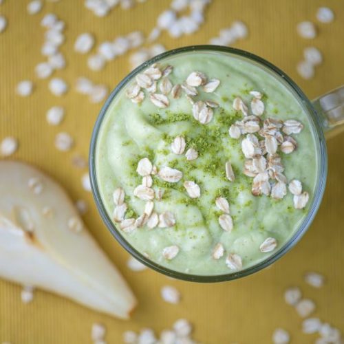 Top View of Green Smoothie Sprinkled with Oats Next to Sliced Pear | Vitacost Blog