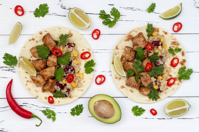 Two Open Tortillas Loaded with Steak and Quinoa on White Wood Surrounded by Colorful Toppings | Vitacost Blog
