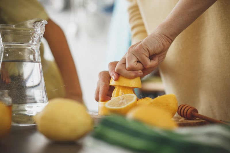 Woman Juicing Lemons on Tabletop with Water Pitcher as Way to Support Healthy Keto Electrolytes | Vitacost.com/blog