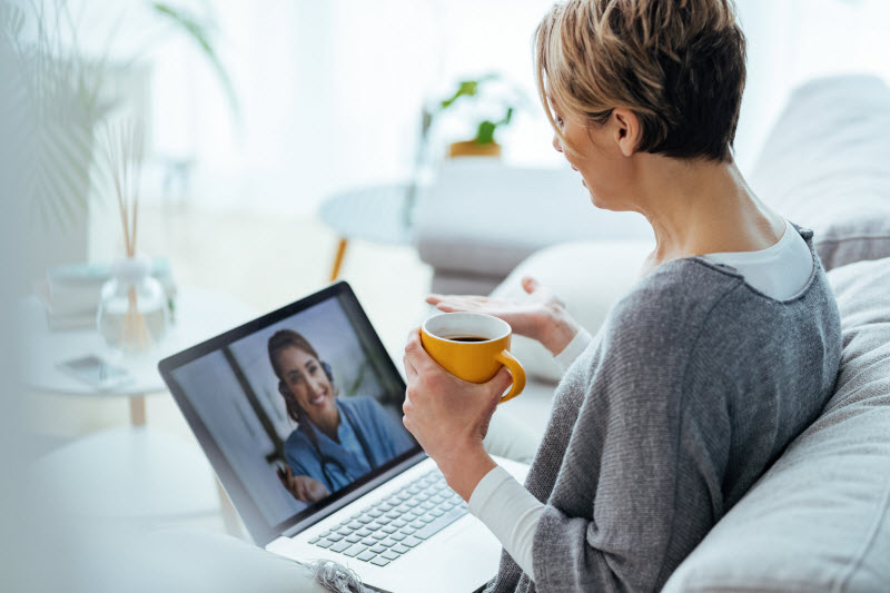 Woman Sitting on Couch With Laptop Doing First Telehealth Visit With Physician | Vitacost.com/blog