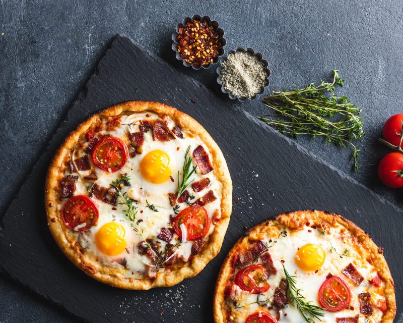 Top View Two Breakfast Pizzas Topped with Egg, Tomato and Bacon | Vitacost Blog