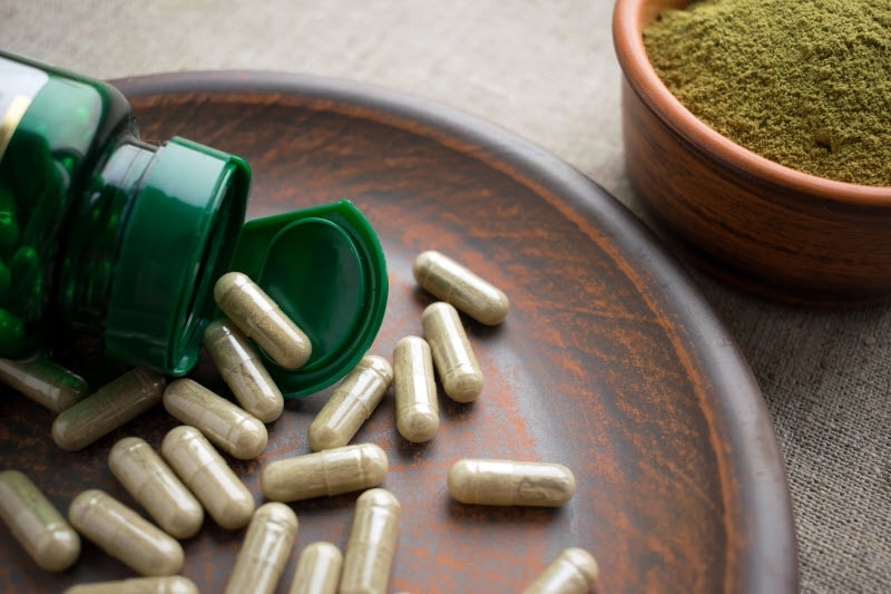 Wooden Dish With Supplement Capsules Spilling From Bottle to Represent How to Take Supplements Safely | Vitacost.com/blog