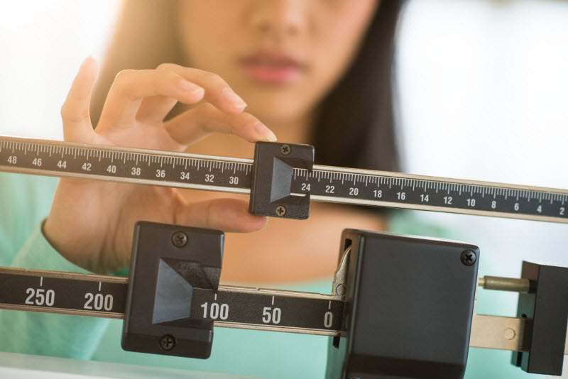 Close-up View of Woman Checking Weight on Manual Scale Wondering Why She's Not Losing Weight | Vitacost.com/blog