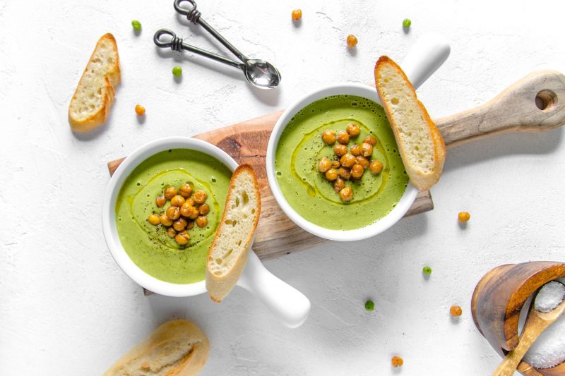 Top View Two Bowls of Green Soup Garnished with Chickpeas and Bread Slices | Vitacost Blog
