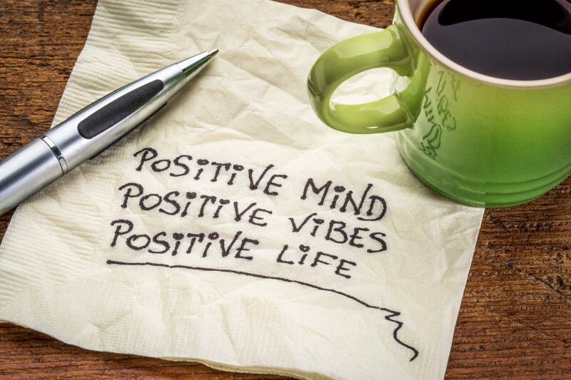 Positive Messages Written on Napkin Beside Mug of Coffee to Represent Optimism and Your Health | Vitacost.com/blog
