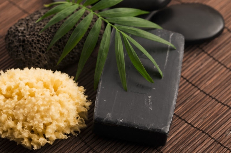 Bar of Black Soap, Natural Sponge & Greenery on Bamboo Mat to Represent African Black Soap Benefits | Vitacost.com/blog