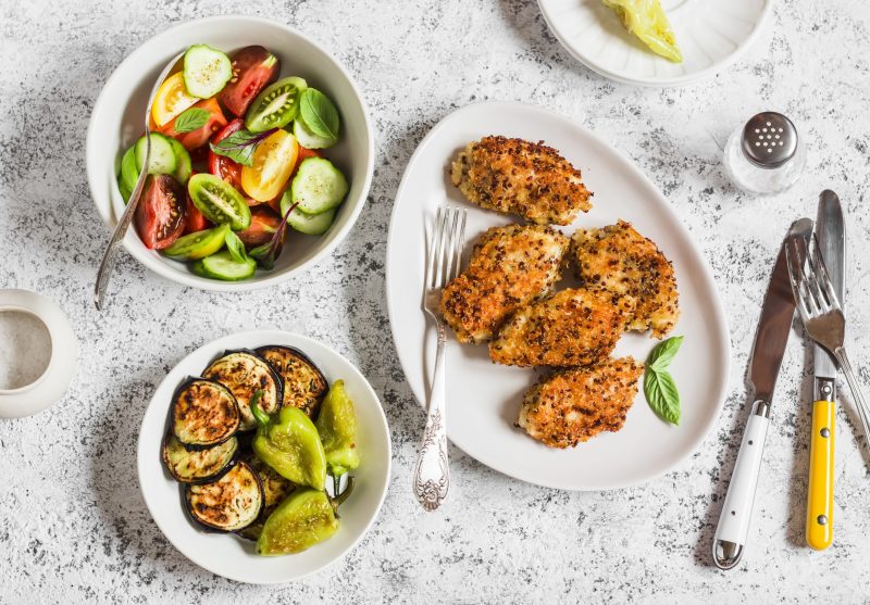 Top View of Crusted Chicken Next to Two Small Bowls of Greens | Vitacost Blow
