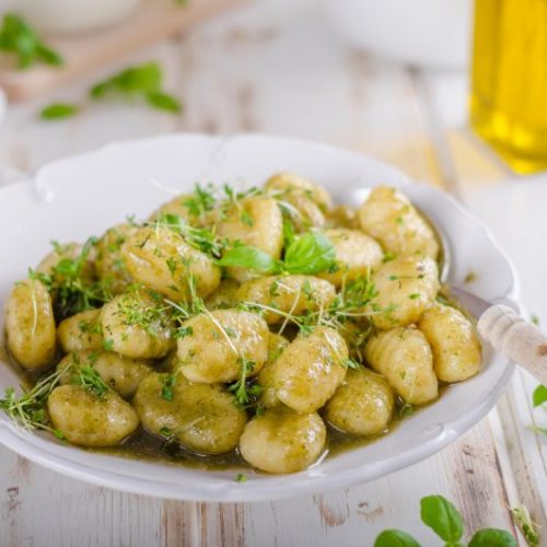 Cauliflower Gnocchi Garnished with Green Herbs in White Bowl | Vitacost Blog