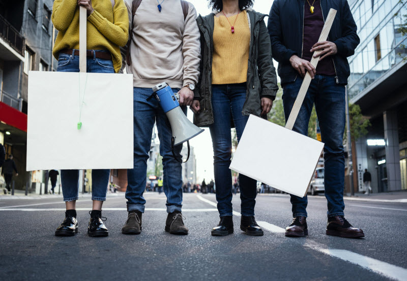 Row of Protestors Holding Signs on Street to Represent the Concept of the Importance of Self Care for Activists | Vitacost.com/blog