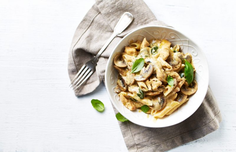 Top View Chicken and Mushroom Penne in White Bowl with Basil Garnish | Vitacost Blog