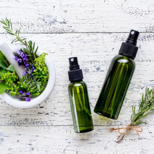 Top View Beauty Spray Bottles on White Wood Next to Bowl of Lavender and Green | Vitacost Blog