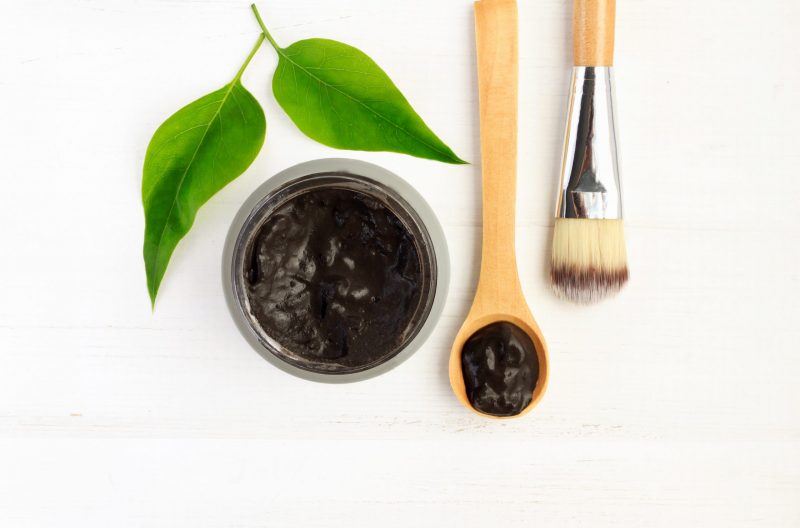 Top View Charcoal Mask in Bowl Next to Wooden Spoon and Brush | Vitacost Blog