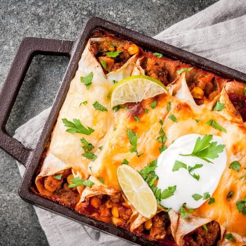 Row of Enchiladas in skillet on gray background
