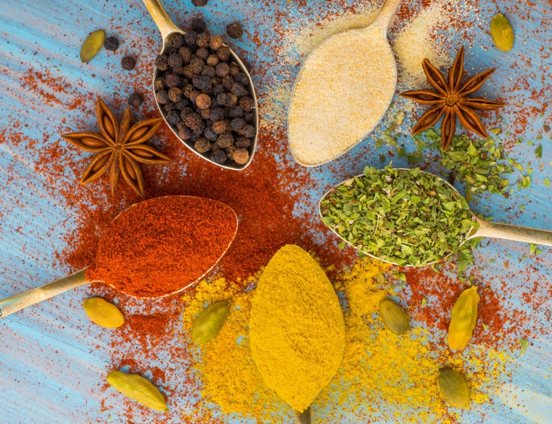 Overhead View of Assorted Spices and Herbs for Inflammation on Wooden Spoons on Blue Surface | Vitacost.com/blog