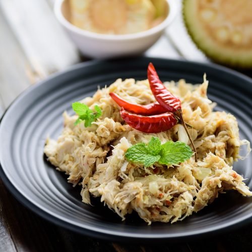 Shredded Jackfruit Garnished with Red Peppers on Black Plate | Vitacost Blog