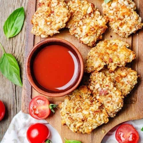 Top View Almond-Coated Chicken Bites on Wooden Serving Board Next to Fresh Ketchup | Vitacost Blog