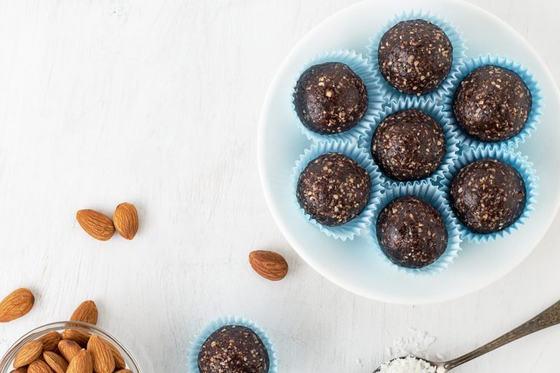 Top View Dark Chocolate Protein Balls on Plate Next to Almonds | Vitacost Blog