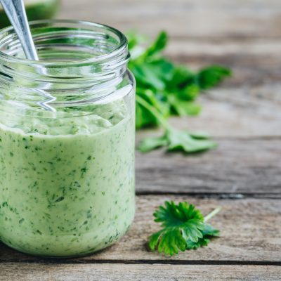 Glass Jar Filled with Creamy Green Sauce Next to Fresh Cilantro and Lime | Vitacost Blog