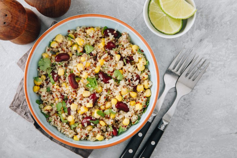 Top View Southwest Quinoa Salad in Bowl On Gray Marble Next to Fresh Lime Slices | Vitacost Blog