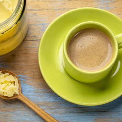Top View Green Mug on Saucer Filled with Brown Liquid Next to Spoon of Ghee | Vitacost Blog