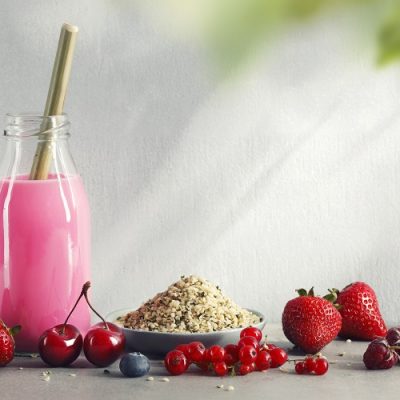 Strawberry Milkshake in Old Fashioned Milk Bottle Next to Pile of Hemp Seeds and Fresh Fruit | Vitacost Blog
