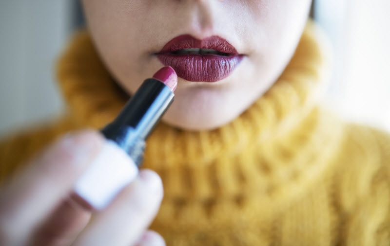 Closeup View of Woman in Yellow Sweater Applying Dark Makeup Lipstick for Autumn Look | Vitacost.com/blog