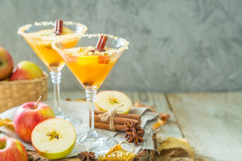 Two Martini Glasses Filled with ORange Liquid Garnished with Apples and Cinnamon | Vitacost Blog