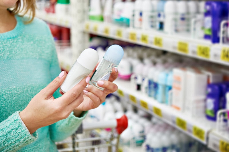 Woman Comparing Labels of Women's Sport Deodorant Products in Store Aisle | Vitacost.com/blog