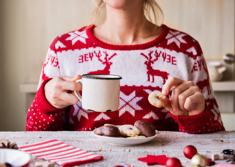 Torso View of Woman Following Holiday Diet Survival Tips Eating Cookies and Drinking Cocoa at Table | Vitacost.com/blog