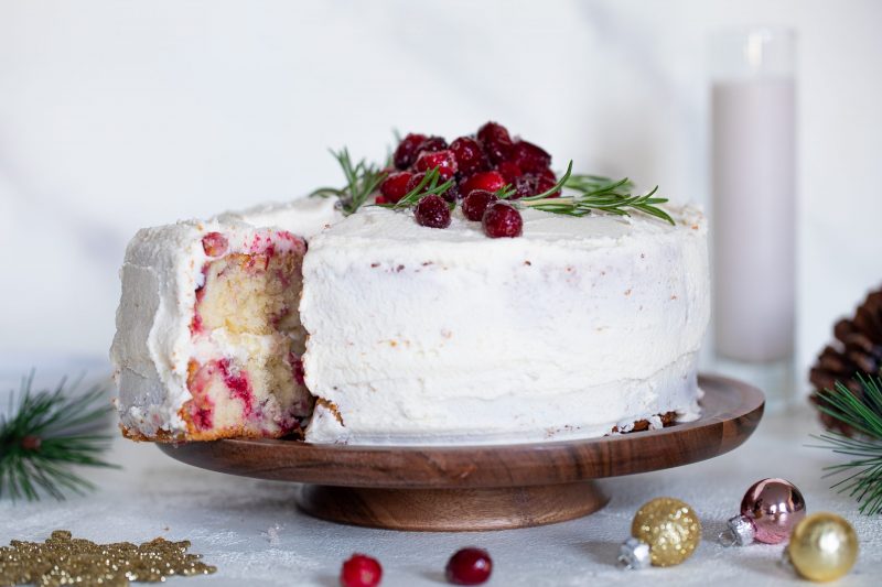 Vanilla-Cranberry Cake with Buttercream Frosting on Cake Stand Garnished with Sugar-Coated Cranberries and Greens | Vitacost Blog