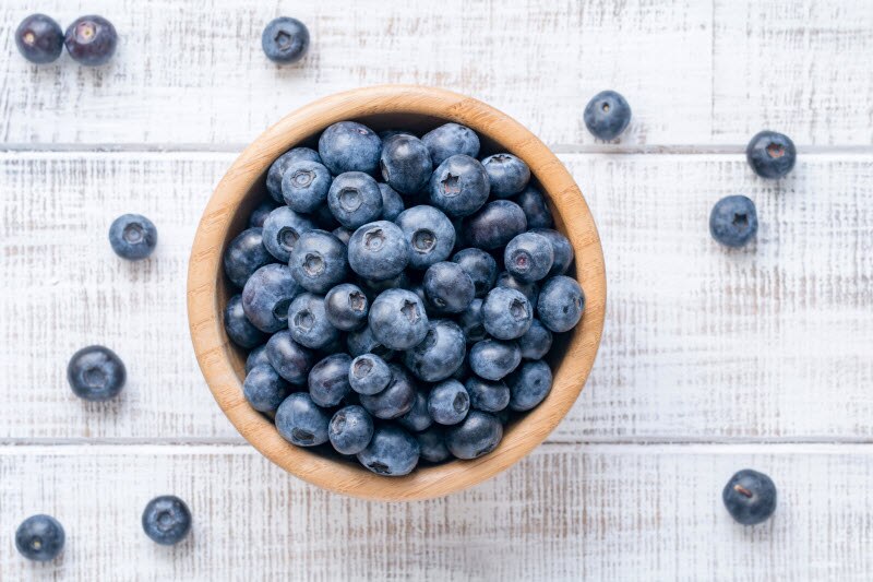 Wooden Bowl of Blueberries on White Wood Surface to Represent What are Flavanols | Vitacost.com/blog