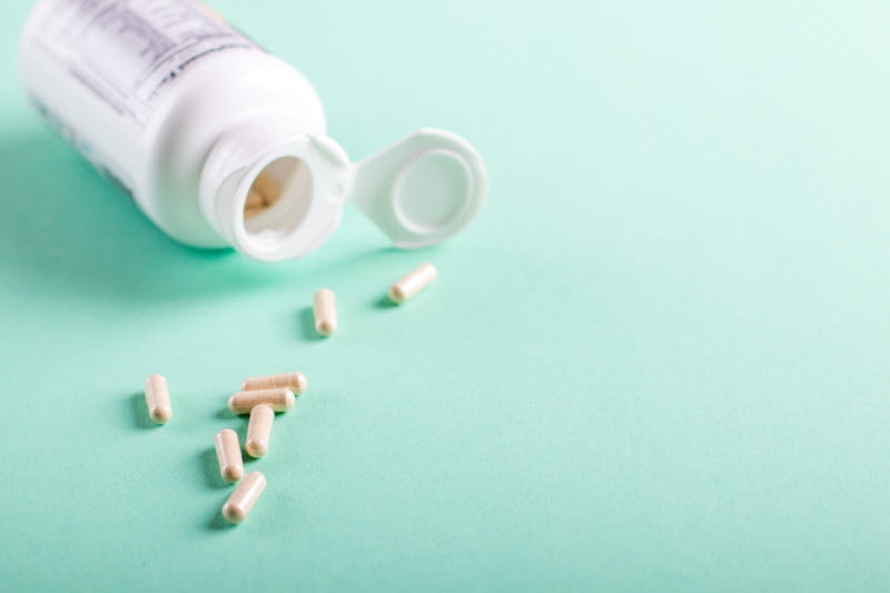 Open White Bottle With Pills Spilling Out to Represent What are Ketone Supplements | Vitacost.com/blog