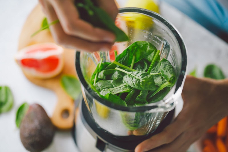 Concept of Creative Blender Uses Represented by Spinach Leaves Being Tossed in Glass Blender on Kitchen Counter | Vitacost.com/blog