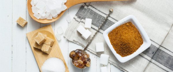 Different Types of Sugar in Spoons, Bowls and Wooden Board on White Wood Surface | Vitacost.com/blog