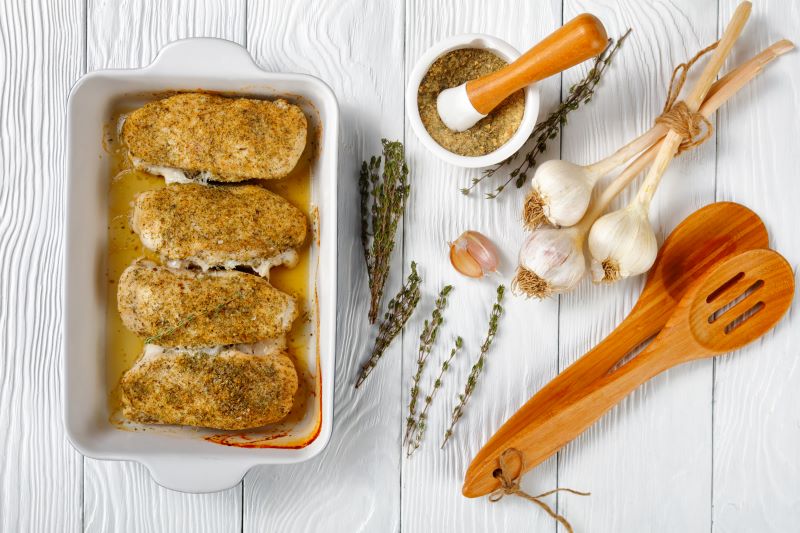 Ranch-Seasoned Chicken Breast in White Baking Dish on Table with Utensils and Garlic | Vitacost.com/blog