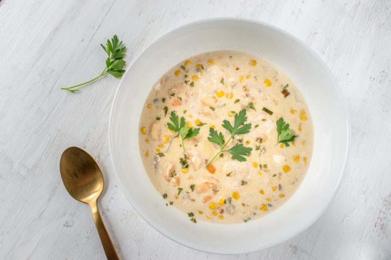 Top View Bowl of Seafood Chowder Garnished with Parsley in White Bowl on White Counter | Vitacost Blog