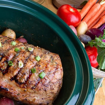 Close Up Pot Roast in Crockpot Surrounded by Colorful Veggies and Garnished with Scallion | Vitacost Blog