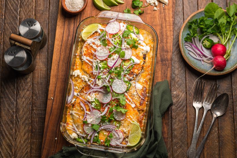 Mexican Lasagna in Baking Dish with Garnishes on Wood Table | Vitacost.com/blog