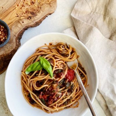 Pasta with Olives, Greens and Tomatoes in White Bowl near Rustic Wood Cutting Board | Vitacost.com/blog
