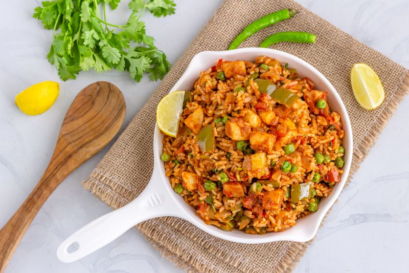 Mexican Rice Recipe with Peppers, Peas and Chicken in White Skillet on Marble Counter | Vitacost.com/blog